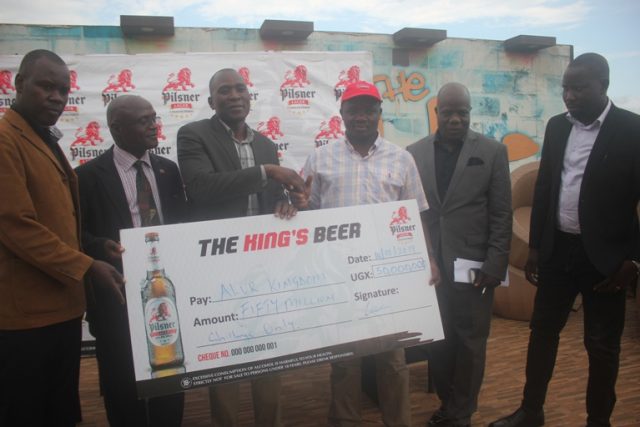 UBL's Kihumuro (red cap) hands over a dummy cheque to Alur officials